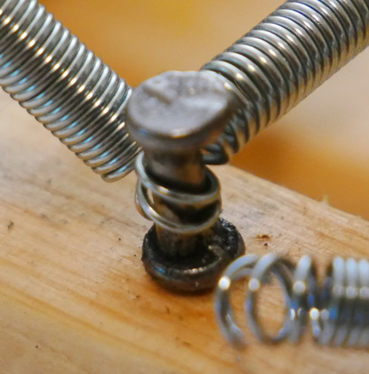 Spring coiled around duplex nail